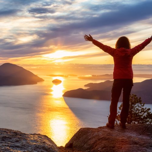 Adventurous,Caucasian,Girl,Standing,On,Top,Of,A,Mountain,During